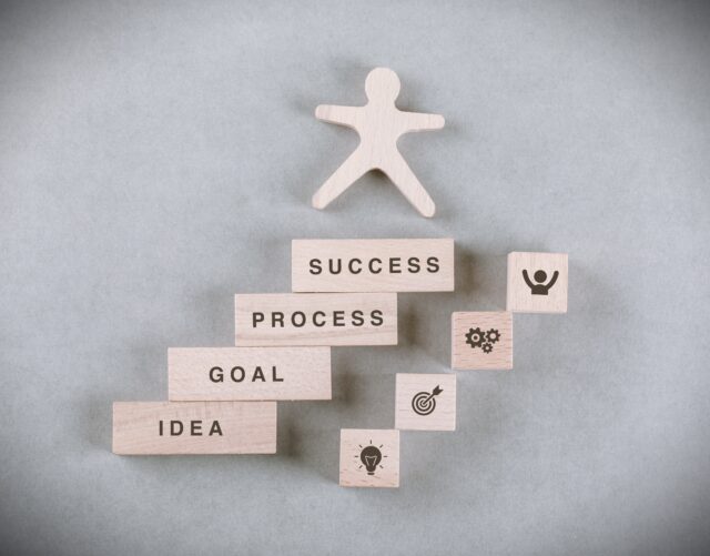 Conceptual of success business with wooden human, rectangle blocks on sage color background flat lay. free space for your text horizontal image